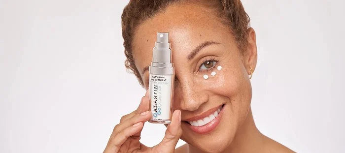 Woman holding ALASTIN Skincare product in front of one eye