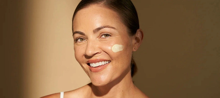 Woman smiling with face cream on cheek