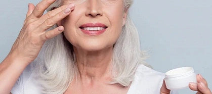 Mature woman applying cream under eyes