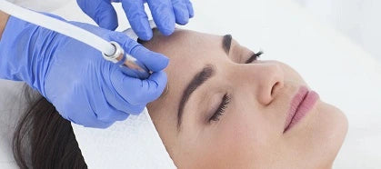 Woman with eyes closed receiving facial treatment