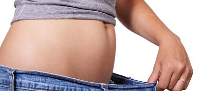Woman pulls jeans in front of stomach